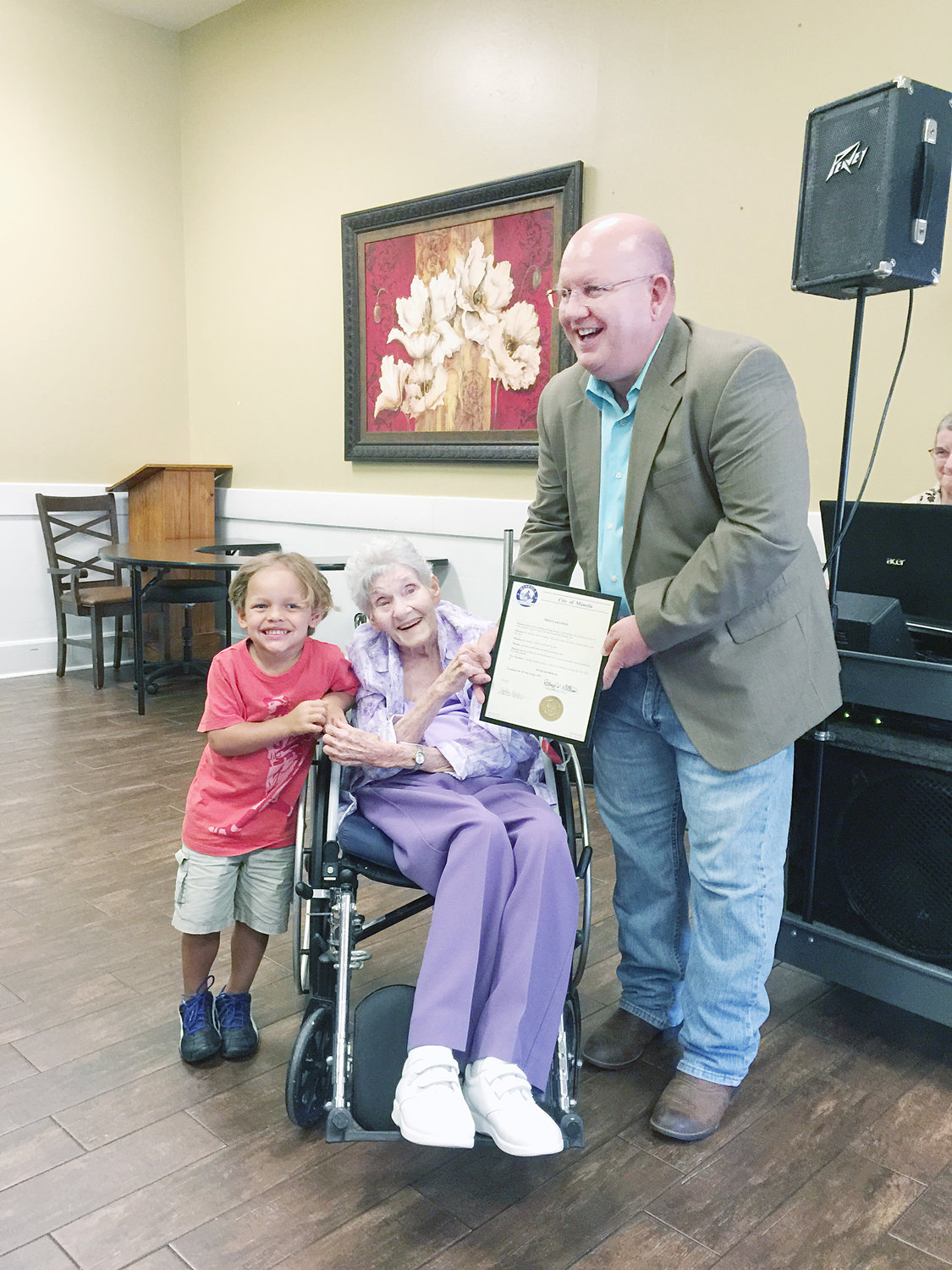 Winnie Booher originally from Grandview now resides in Wood Memorial Nursing Home and calls Mineola home. She turned 100 on July 31 and was honored by the City of Mineola at her birthday celebration. Mayor Pro-tem Kevin White, far right, proclaimed July 26 as Winnie Booher Day in the City of Mineola! Pictured with Ms. Booher is Elijah Coffman. His grandma was caregiver to Winnie for two years. Winnie helped care for him and a special bond was formed from the start. He still visits Winnie and when she sees him her face lights up! (Photo courtesy Stacey Hays)
