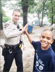 Wood County Sheriff’s Deputy Kevin Atkinson gets the high-five from a young man at the appreciation fete held at Jim Hogg City Park in Quitman last Thursday.