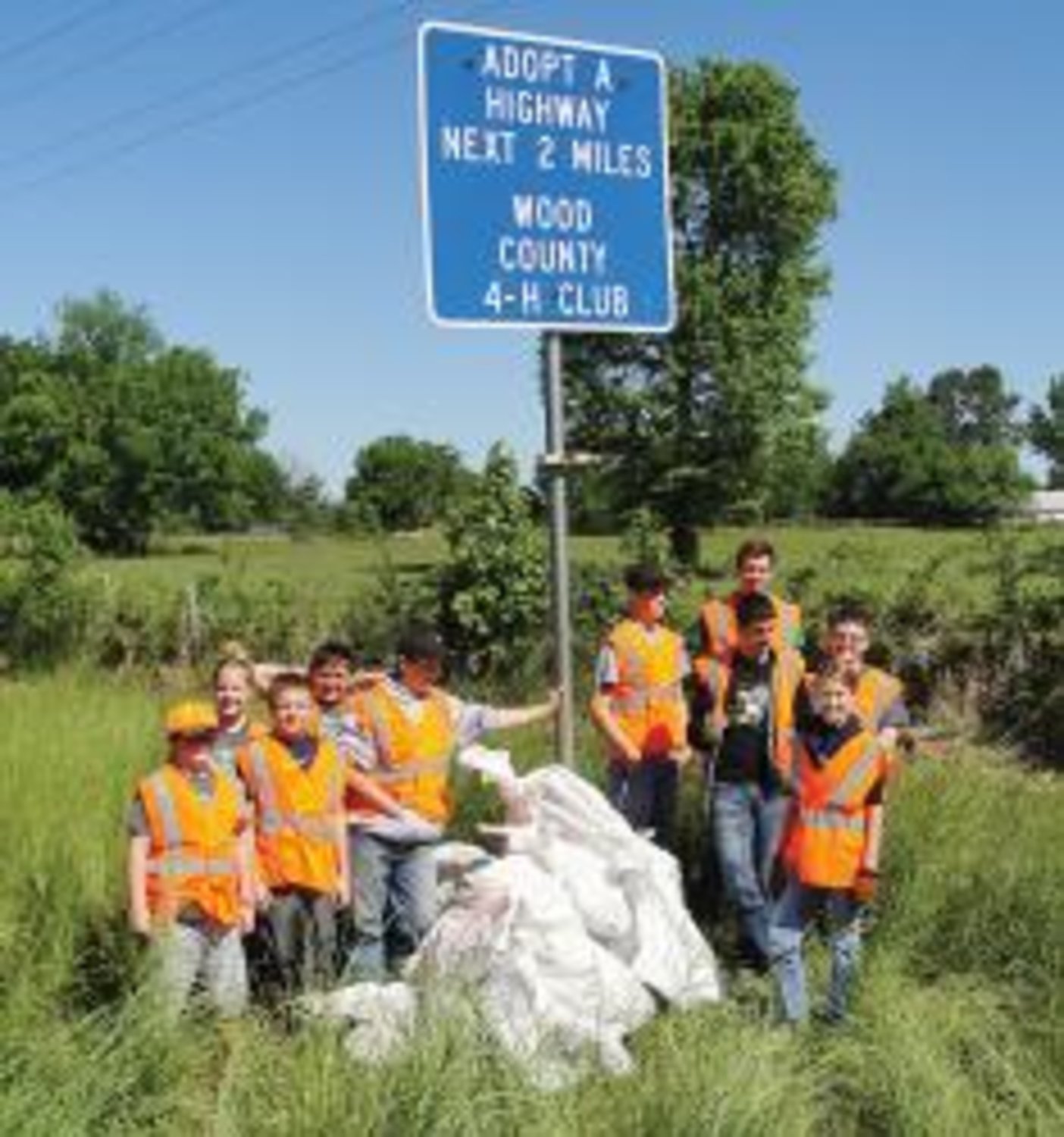 After a long day of picking up trash, members of the Wood County 4-H club gather around their highway sign.