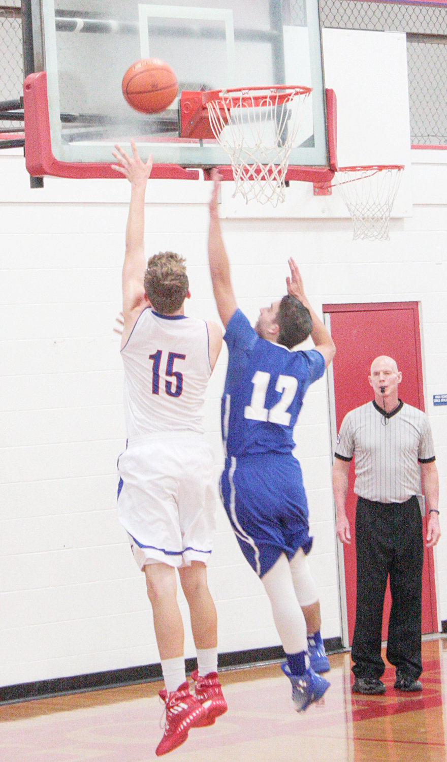 Dawson Kirk (15) goes up for one of his seven baskets Friday night in Alba-Golden’s season opener against Hawkins. The Hawks’ Mark Pope (12) contested Kirk hard at the bucket, but could not make the block and stop the score.