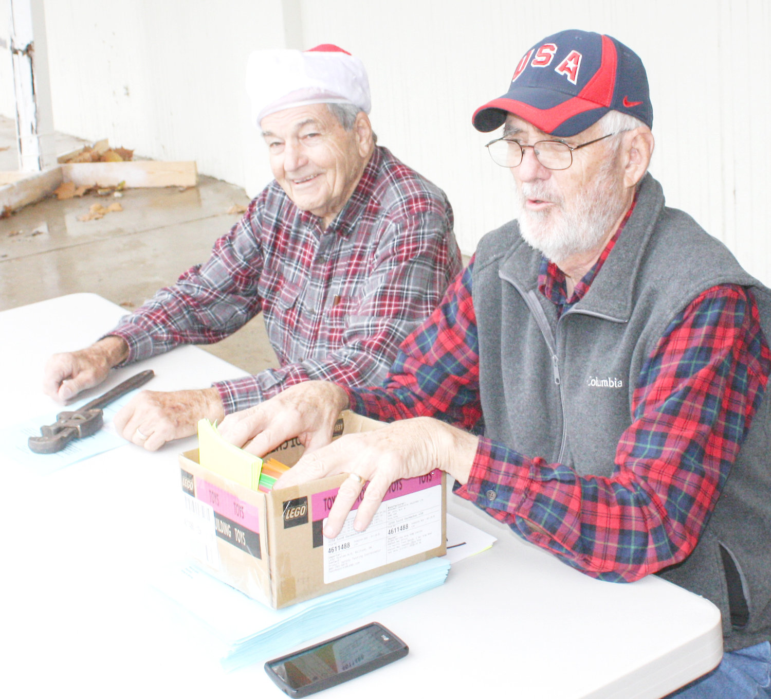 Manning the check-in table at Saturday’s Mineola Caring & Sharing Christmas distribution were Wayne Williams, right, and Gene Strause. Williams has been a volunteer for this project for over 20 years.