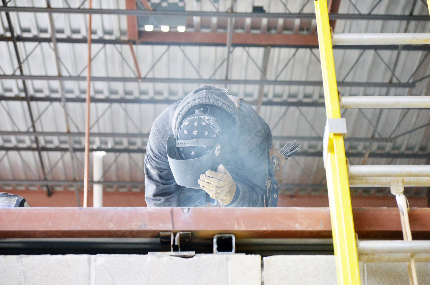 A construction worker is working in the loft area of the new band hall.