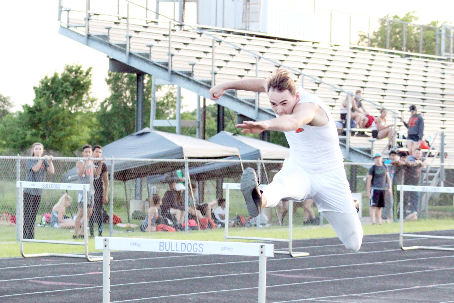 Devon Goguen leaps over the hurdle in the 300M hurdles event. (Monitor photo by Briana Harmon)