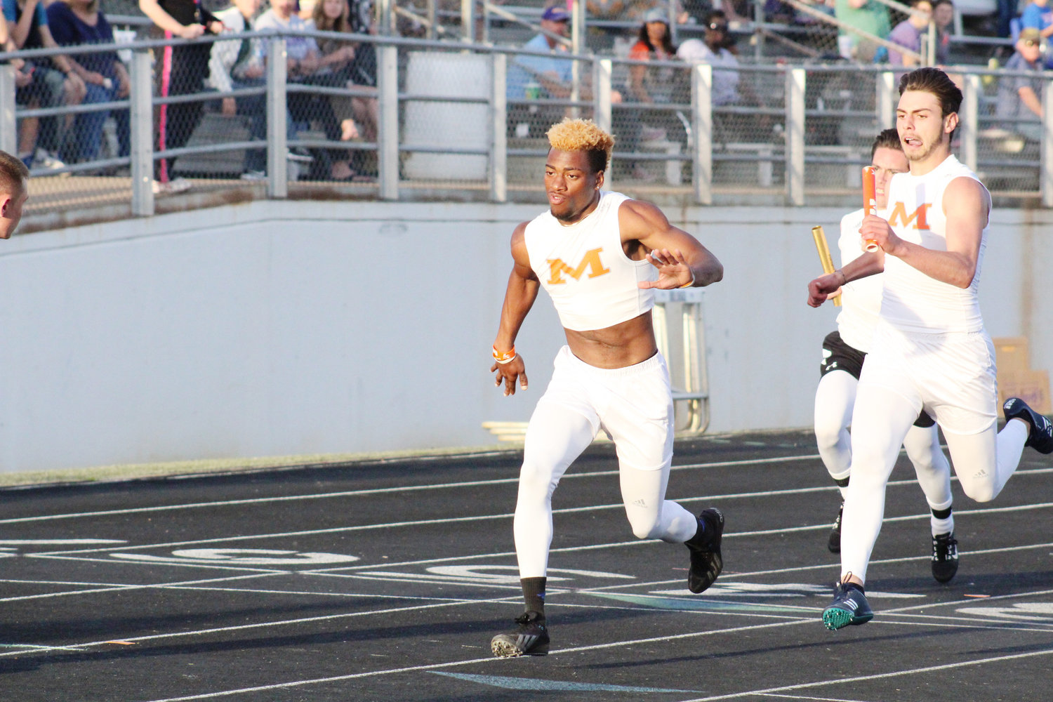 Dalton Harris hands off to the baton to Kartney Hampton in the men’s 4x200 varsity relay. The Mineola relay team finished 2nd place in the event but set a new school record with a time of 1:30:65. (Monitor photo by Briana Harmon)