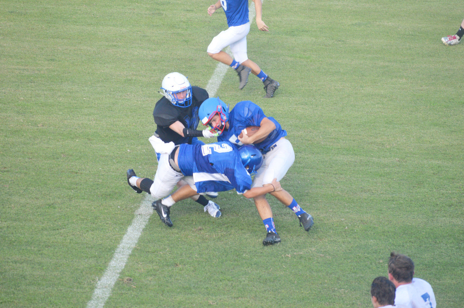 Josh Medlin (5) is brought down by a pair of Hawkins Hawks in Thursday’s scrimmage.