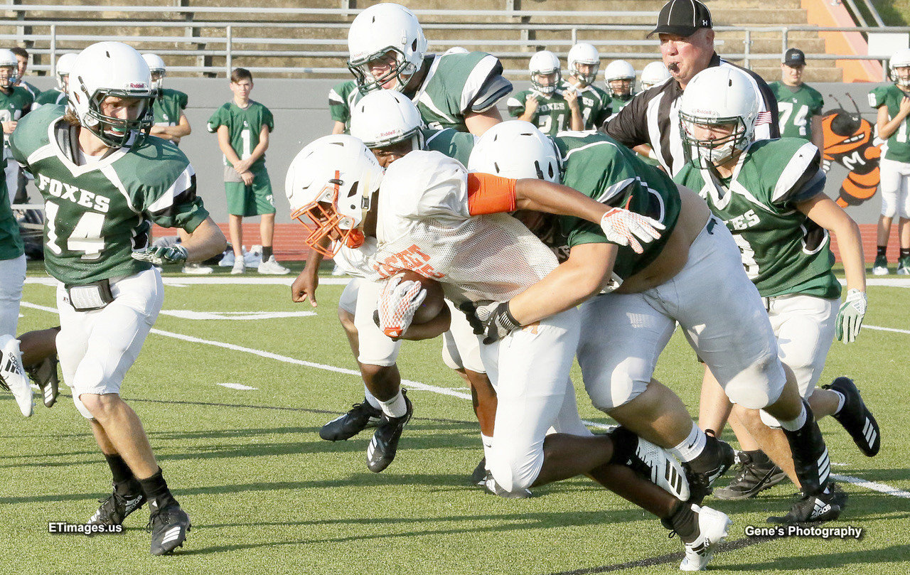 A Mineola running back is hauled down by a Caddo Mills defender in last week’s scrimmage at Meredith Memorial Stadium.
