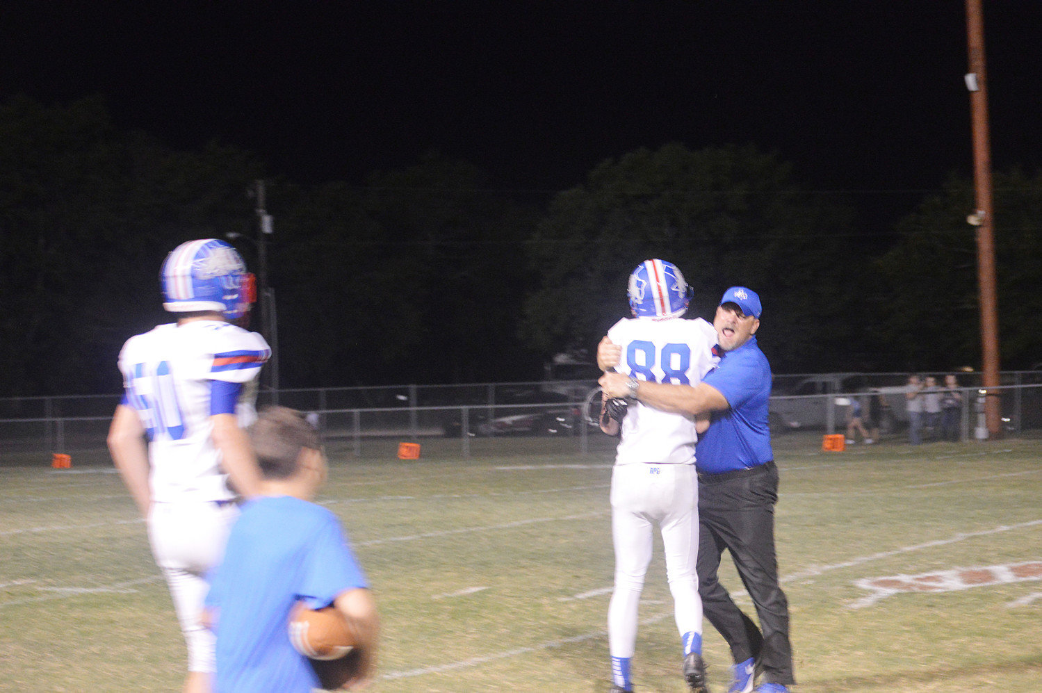 Quitman’s Riley Flanagan (88) meets Coach Bryan Oakes at midfield to celebrate the Bulldogs’ 30-6 win over Cumby.