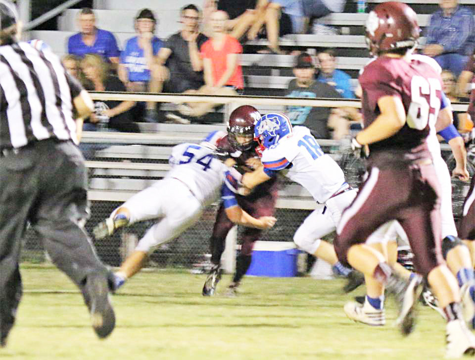 David Tarno (54) and Dylan Coe (18) stop a Cumby runner cold in the Bulldogs win Friday night.