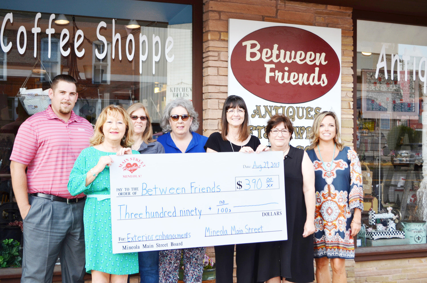 Main Street Director Doris Newman, left, presents a $390 check to Donna Hanger, owner of Between Friends at 114 E. Broad Street. Back row from left are Main Street directors Nic Watkins, Allison Utley, Pat Hamlett, Wanda Dubbs and Misty Hooks. The fund went toward improving the business’s sign.