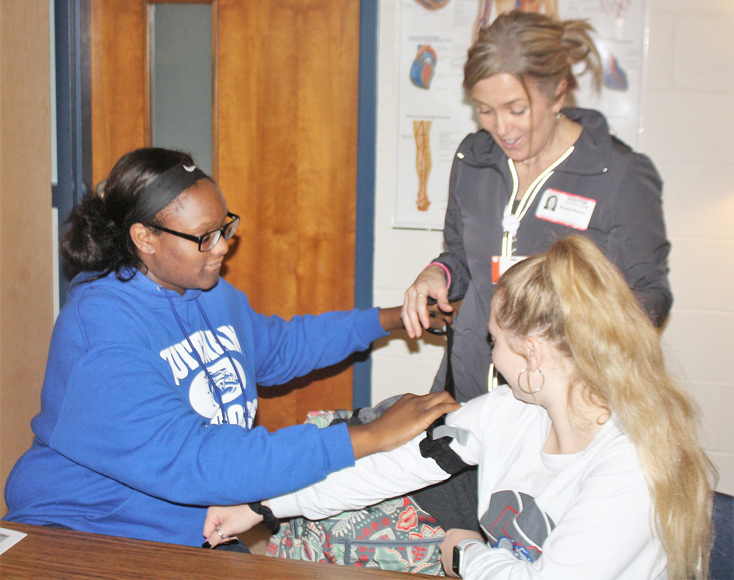 Assisted by UT Health Quitman nurse Ronna Reaves, Quitman High School health student Utopia Henry (left) wraps a tourniquet around classmate Ashlynn Cockerham (right) during the UT Health East Texas EMS “Stop the Bleeding” training.  (Monitor photo by Zak Wellerman)