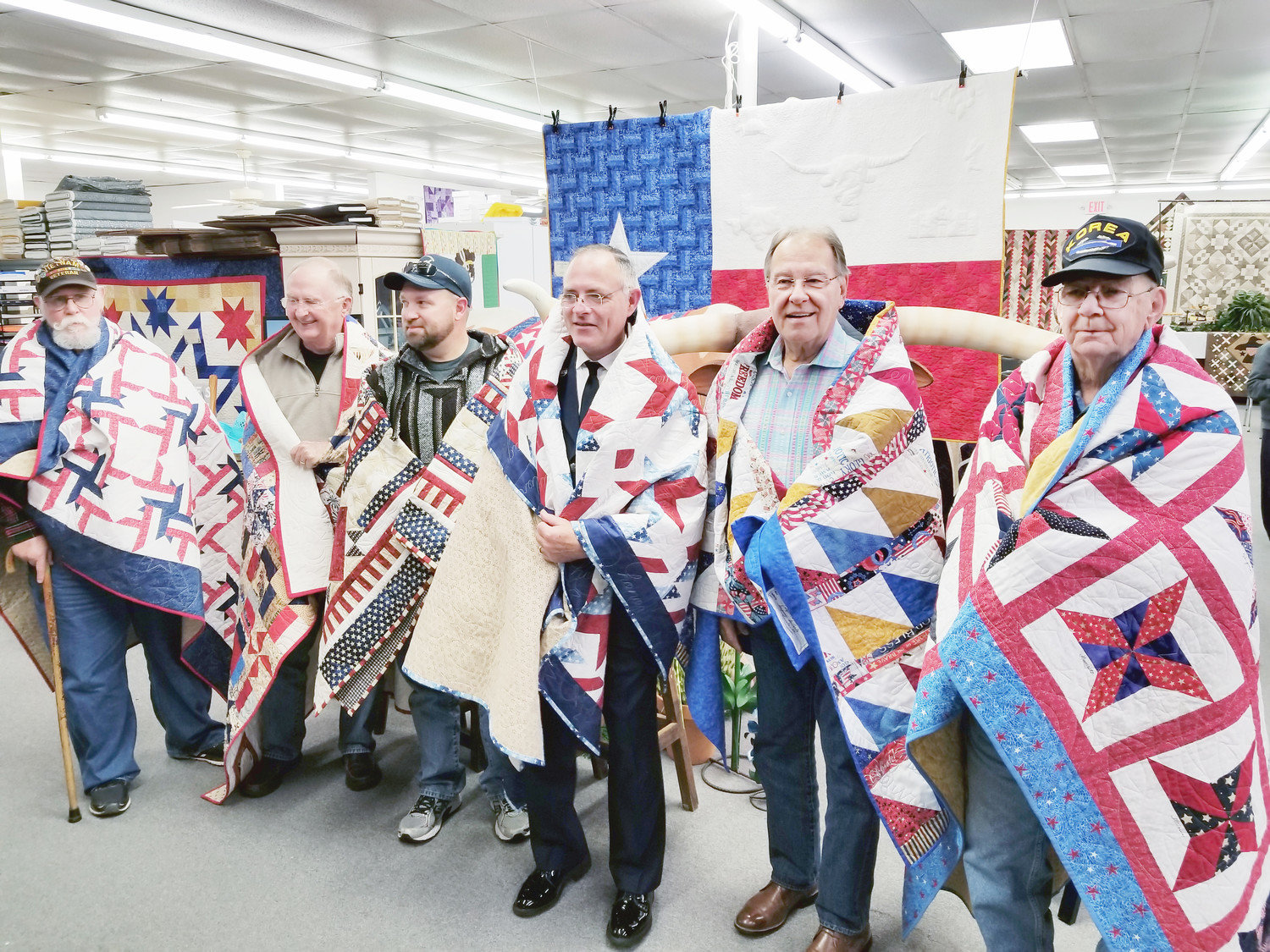 Quilts are made with love and have always been a symbol of warmth and comfort.  Quilts of Valor mean even more.  They provide a way for citizens to give back and serve our service members and veterans.  Saturday, six veterans were awarded Quilts of Valor at Stitchin’ Heaven in Mineola. From left are: Bruce Walker, Navy; Richard Fairbanks, Marines; James Wilson, Army; Ben Hudman, Air Force; Joe Hamby, Army; and John Burns, Army. THe QOV sewing group meets the last Wednesday of each month at Stitchin’ Heaven. To learn more, visit visit www.QOVF.org (Courtesy photo).