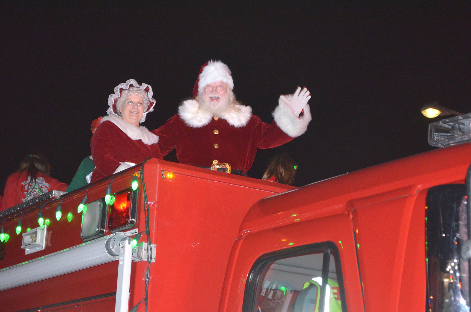 Santa and Mrs. Claus wave to the crowd Saturday evening from aboard a fire truck during the Mineola Chamber of Commerce’s annual Christmas parade. A crowd estimated at close to 1,000 people lined Broad Street to take in the festivities, which included dancers, a marching band, and beautifully lit floats. (Monitor photo by Hank Murphy)
