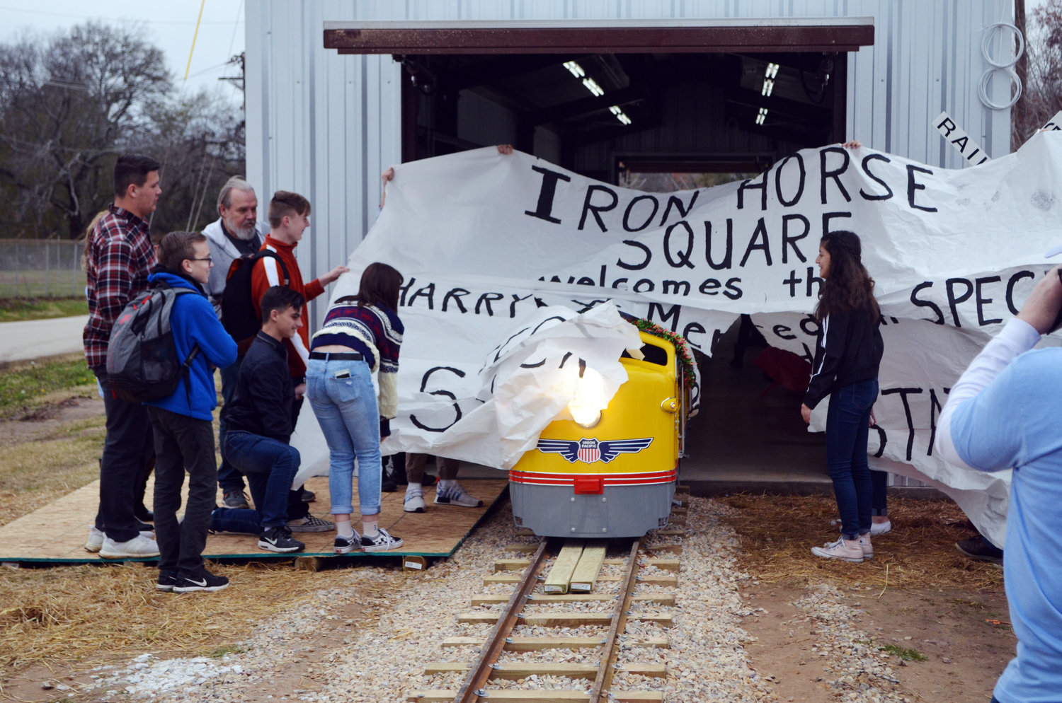 The Harry Meredith Special bursts through a giant paper sign last week as it emerges from Steck Station to make its maiden journey at Iron Horse Square Park in Mineola.