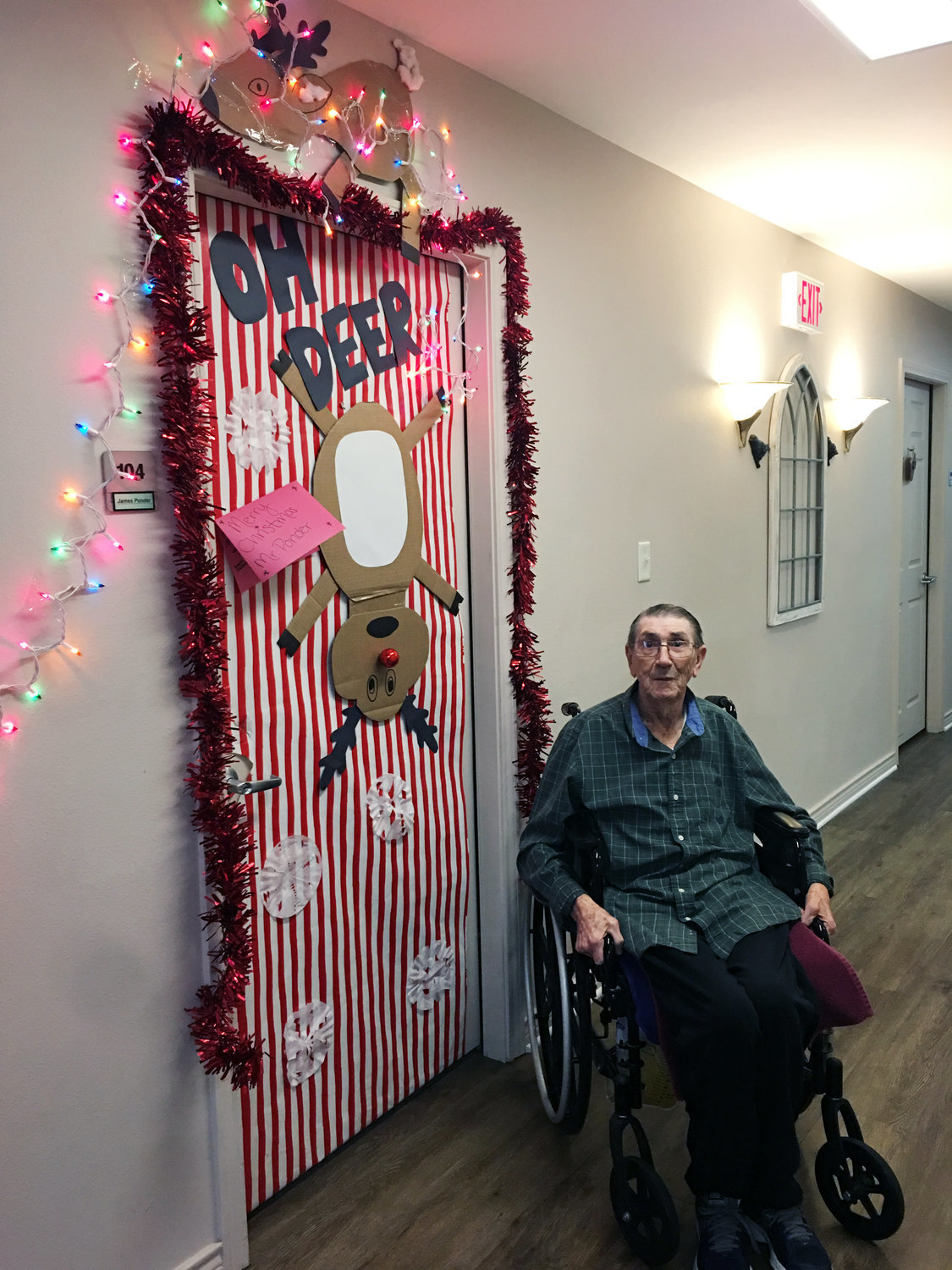 Wesley House resident James “T-Bone” Ponder sits next to his decorated door made by Quitman High School athletes.