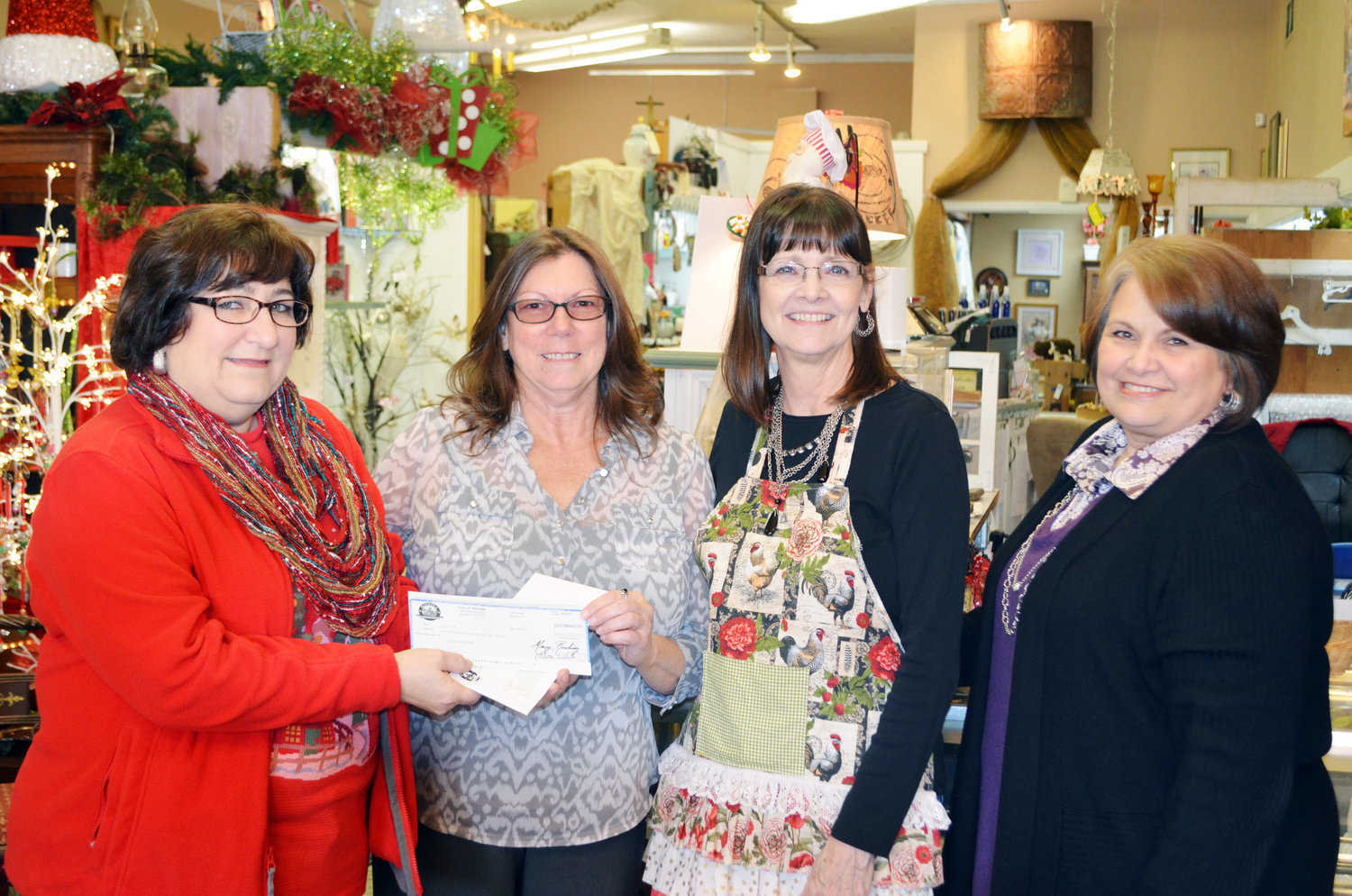 From left, Wanda Dubbs, president of the Mineola Main Street board, presents a $200 check to  Laura Edwards, a winner in the Shop Local Mineola contest, at Just Between Friends gift shop on Broad Street on Dec. 18. While shopping downtown, Edwards made a purchase at Just Between Friends and entered the receipt into the contest. Also pictured are Donna Hanger, owner of the Just Between Friends, and Lynn Kitchens, director of marketing for the City of Mineola. The campaign covers purchases made between Nov. 23-Dec. 28. To participate, you must make a purchase at a local restaurants and retail business (no “big box” stores or supermarkets). Taking a picture of your receipt, your purchase and where you got it and post it to Facebook with #ShopLocalMineolaTX. Or take your receipt or a copy to either Mineola Community Bank’s main branch, their Brookshire’s branch, the Chamber of Commerce or City Hall.