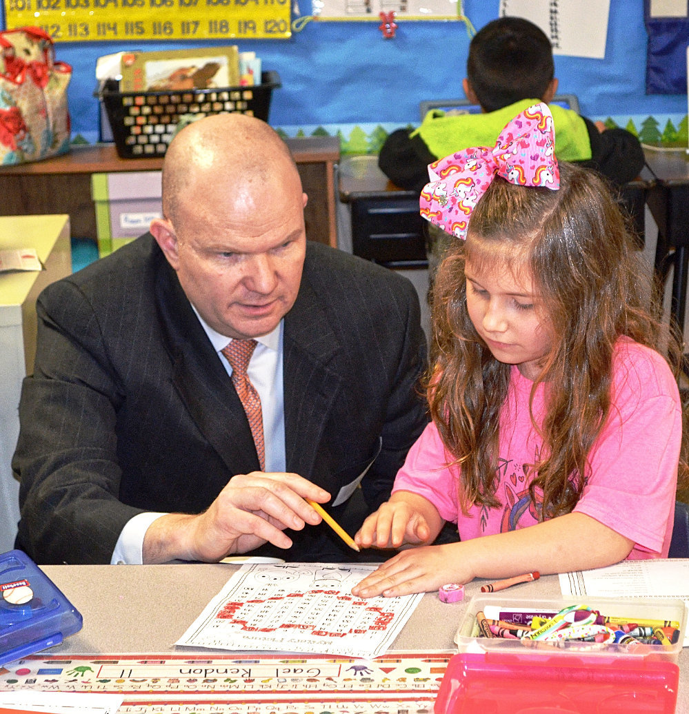 Martin Winchester, TEA deputy commissioner for educator support, sits with Mineola first-grader Anniston Tibbs as she explains her classroom work.