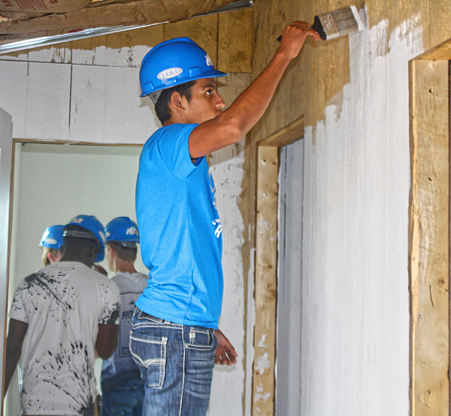 Quitman High School sophomore Marianno Lara paints one of the walls of the geometry class’s tiny house on May 3.