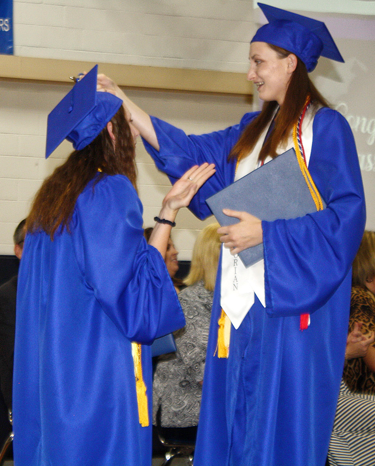 Salutatorian Maggie Hooker of Yantis High School turns her sister Maddie Hooker’s graduation cap tassel during the graduation ceremony on Saturday at the high school gym.