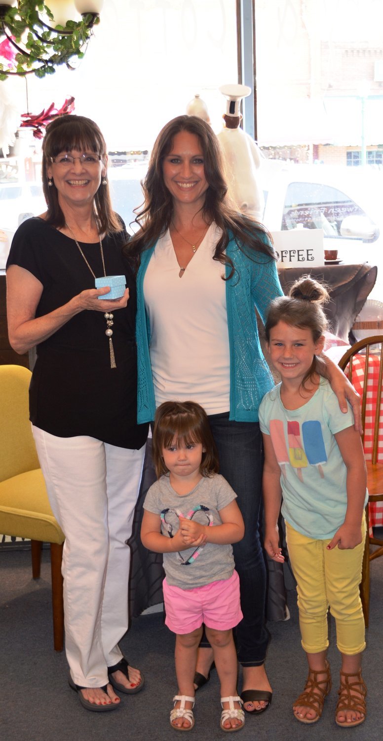 From left, Donna Hanger, owner of Between Friends in Mineola, Kerri Hefner, and her two daughters Ellie and Ava, right. Hanger holds a package similar to the 350 she packed with fudge for the Legislative Ladies Club’s Taste of Texas event in May.