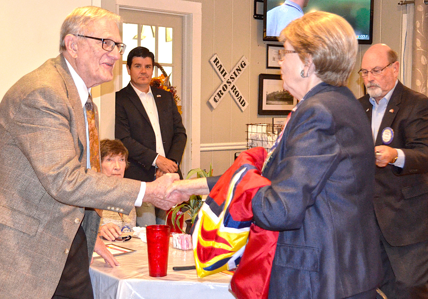 Bill Knight is congratulated by Mineola Rotary Club member Mary Lookadoo upon receiving the Honor and Remember Flags for his brothers who were killed in combat during Wolrd War Two and Vietnam.