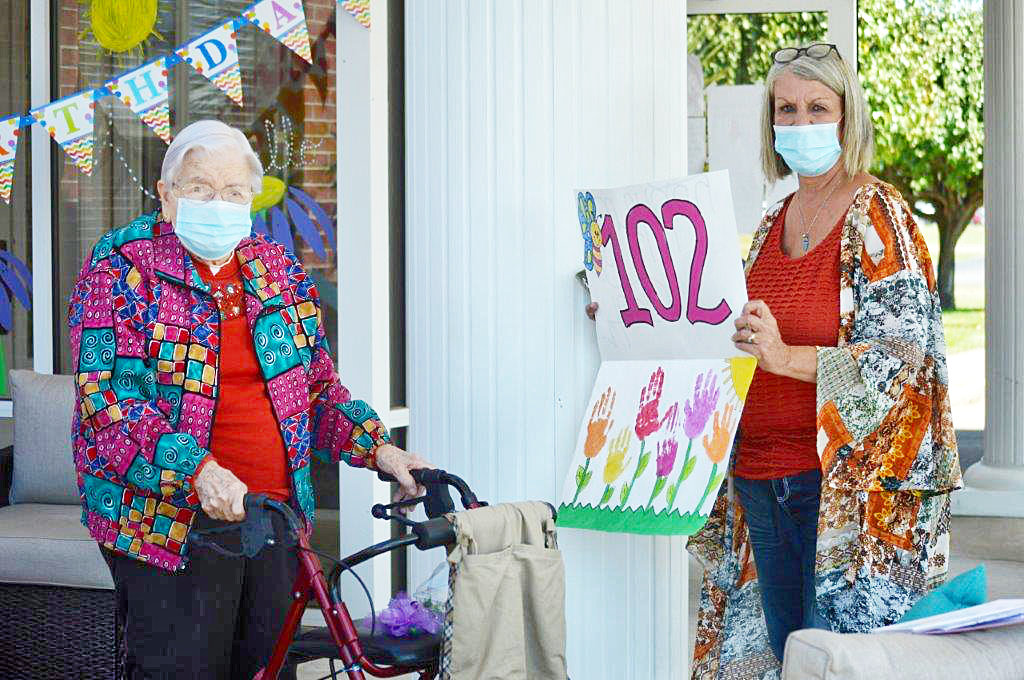 Bernice Vandeventer (left) is shown a card celebrating her 102nd birthday by Tammy Purdy during an outdoor celebration last week at Wesley House in Quitman. Two busloads of students from Wood County special education classes came to sing Happy Birthday and help her celebrate the occasion.