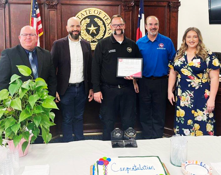 Wood County Fire Marshal and Emergency Management Director Tully Davidson received a surprise award as a 2022 “Difference-Maker” Monday afternoon in the county courtroom by representatives from the Texas Association of Counties. From left are Wood County Judge Kevin White, TAC Risk Control Consultant Isaac Garcia, Davidson, TAC Risk Management Consultant Todd Kisel and TAC Human Resources Consultant Halie Bever.