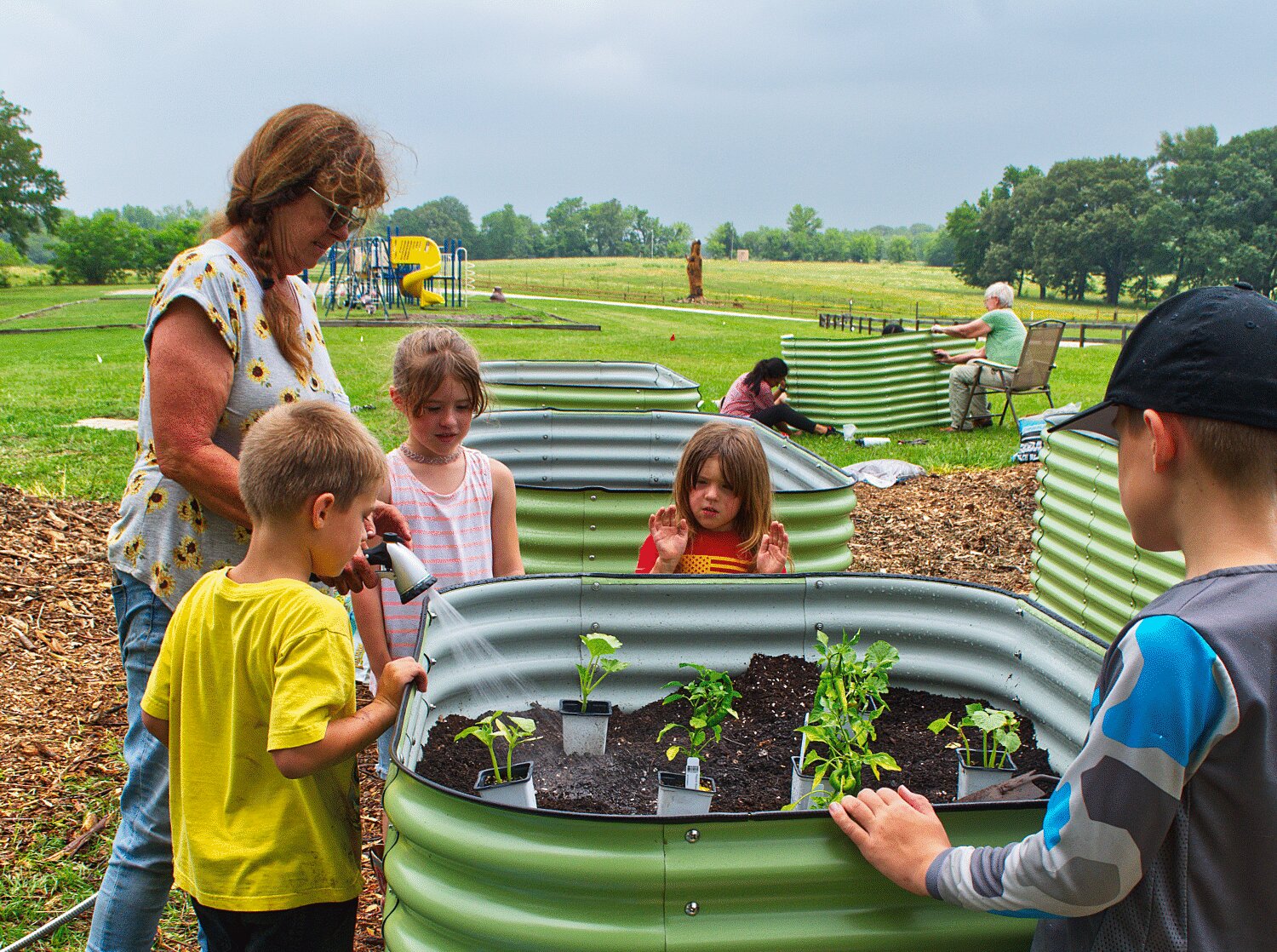 Elisabeth Dry directs a group of children planting the first raised bed at the new Promise of Peace garden at the Mineola Nature Preserve last week.
