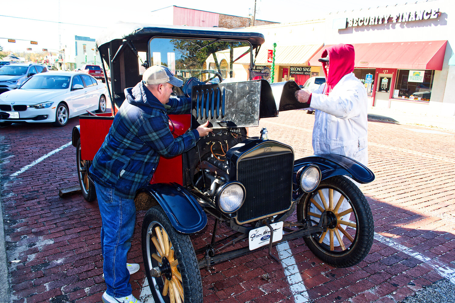 Patrick Lewis and Todd Touchberry replace the cowling on the 1920 Model T after making a minor roadside repair in downtown Mineola. See Page 12A for more photos.