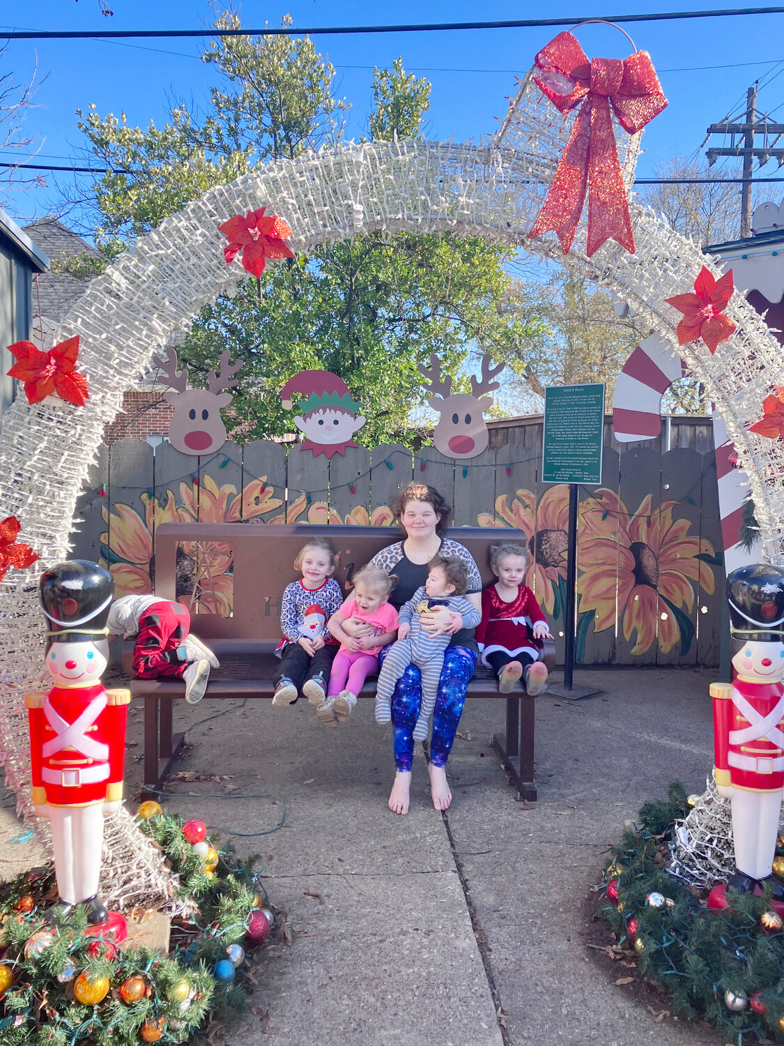 The Burge family under one of the many decorations associated with Santa’s Little Red House, the light-up wreath.