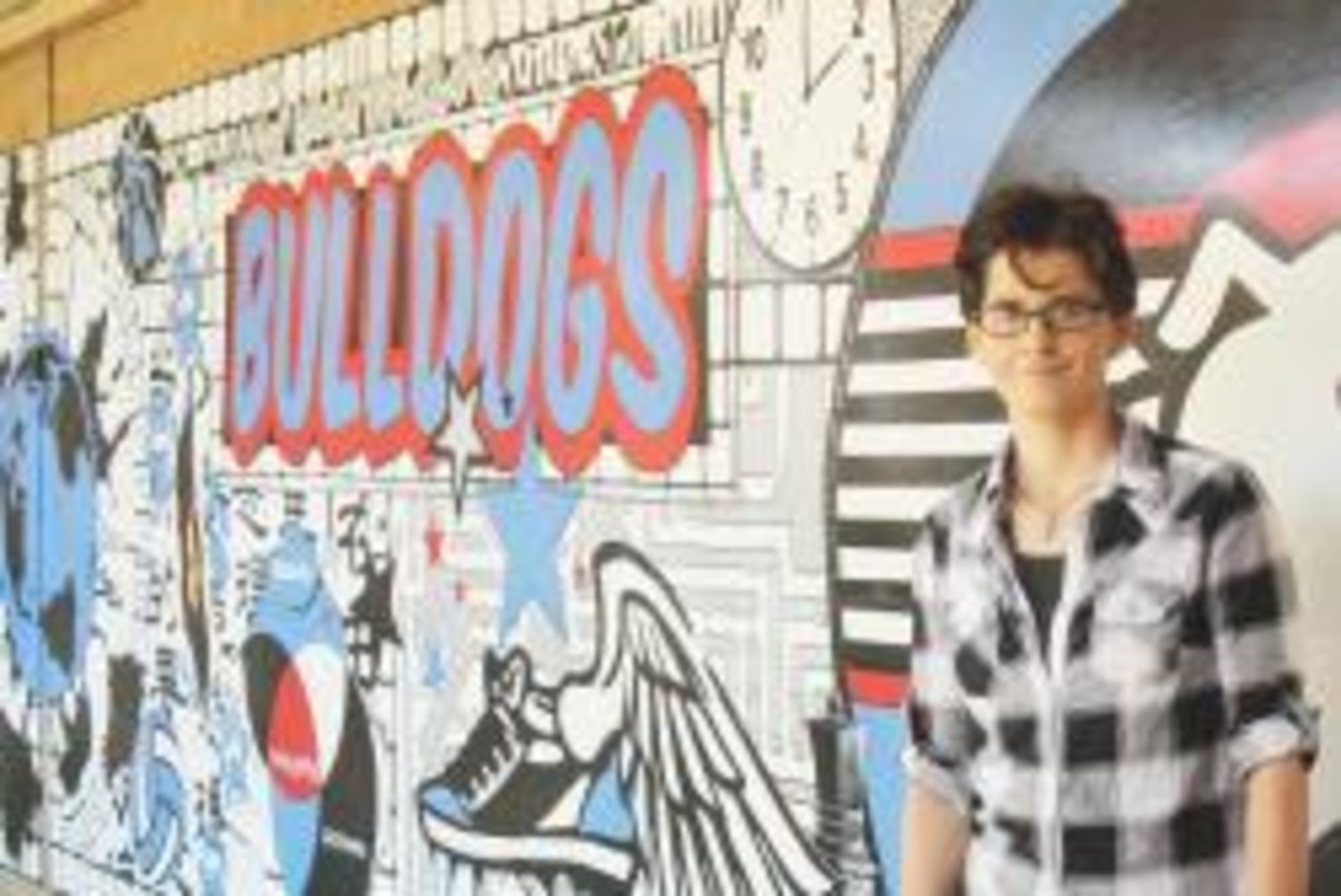 Local artist Erica Fry stands with the mural she created for the atrium of the Quitman Junior High School.