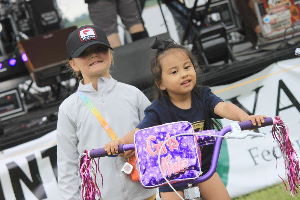 Bicycle winner Rosie Vazquez won a bicycle at the BassMasters Elite Tournament Sunday. Standing behind her is Layken Stokes who donated the bike back to the drawing because she had just received a new one and wanted someone else who needed a new bike to win.