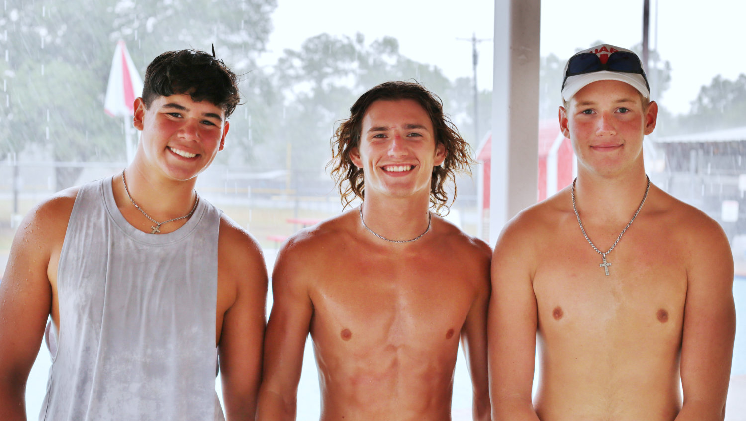 Three of the Quitman City Pool lifeguards, from left, Tristan Eley, Adam Blalock and Nicholas Eley, take cover while a localized downpour temporarily delayed pool activity on a recent Friday afternoon.