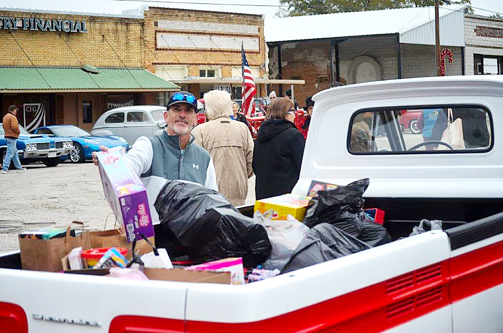 Quitman city Alderman Steve Glenn brings a toy to add to the donations being made by the Lake Country Classic Cars Club which will bring smiles to a lot of foster kids at Christmas. Saturday was the final Coffee and Cars event on the square in Quitman until next spring.