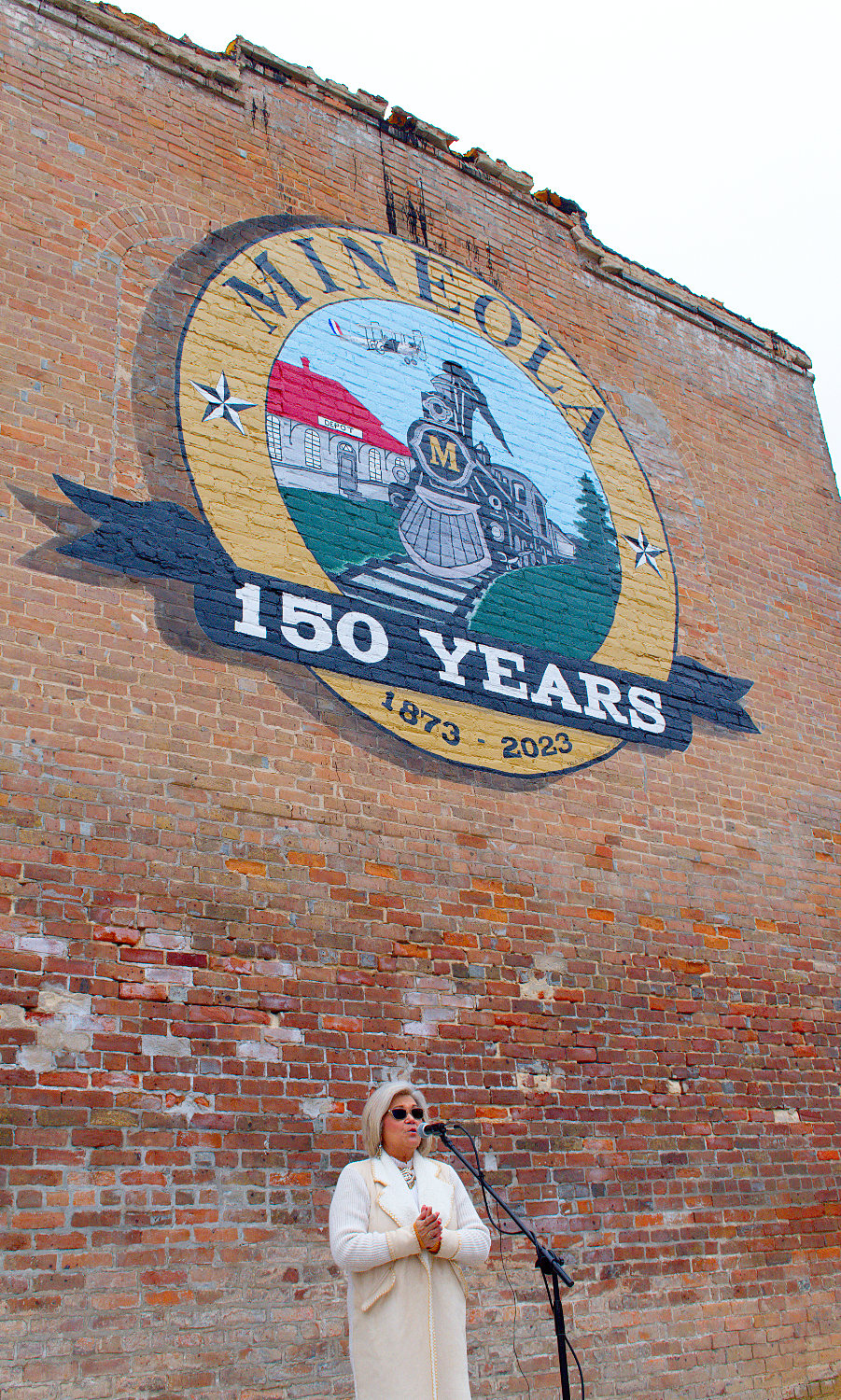Mineola City Manager Mercy Rushing addresses the dedication Friday of the city’s sesquicentennial mural adorning the south wall of the Rushing building on S. Johnson St. Mayor Jayne Lankford read a proclamation concerning the city’ yearlong plans to celebrate its 150th anniversary in May. Erica Fry painted the mural of the official logo. Numerous events are planned throughout the year, as well as additional activities during the city’s regular events.
