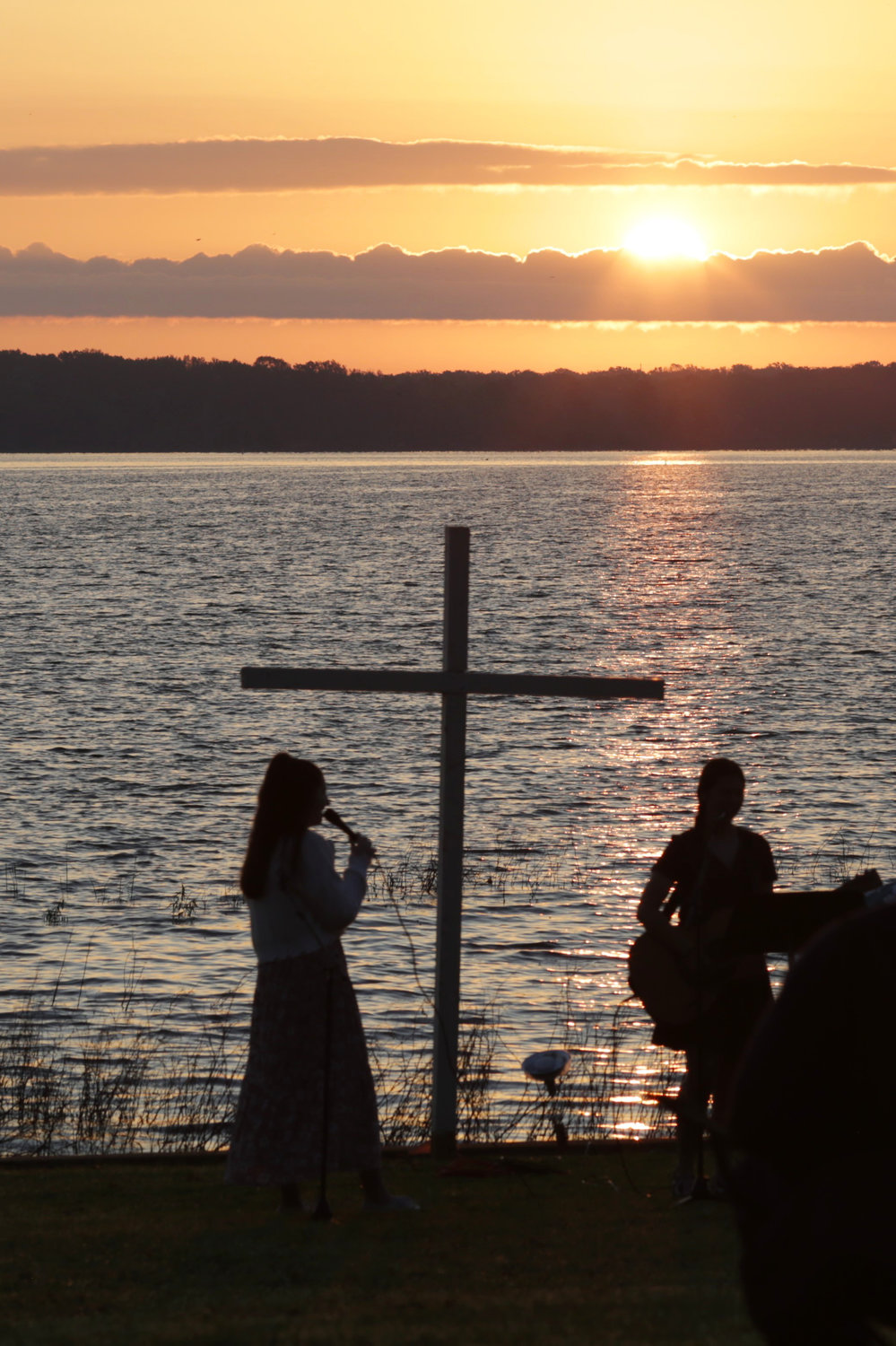 The rising sun over Lake Fork Sunday morning silhouettes musicians performing during an Easter sunrise service by the Lake Fork Baptist Church.