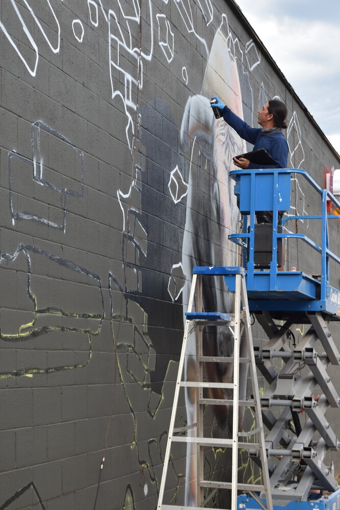 Muralist Luis Valle works on the mural on the south wall of The Smoke Shop on S. Pacific St. in Mineola Monday.